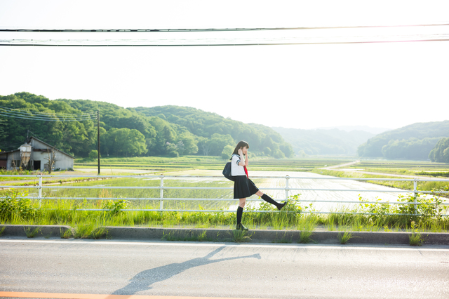 young high school japanese girl walking across a bridge in the japanese countryside