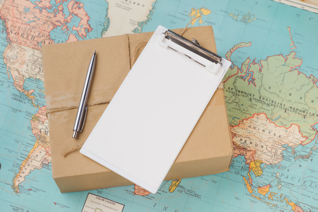 Pen and clipboard on package with world map underneath