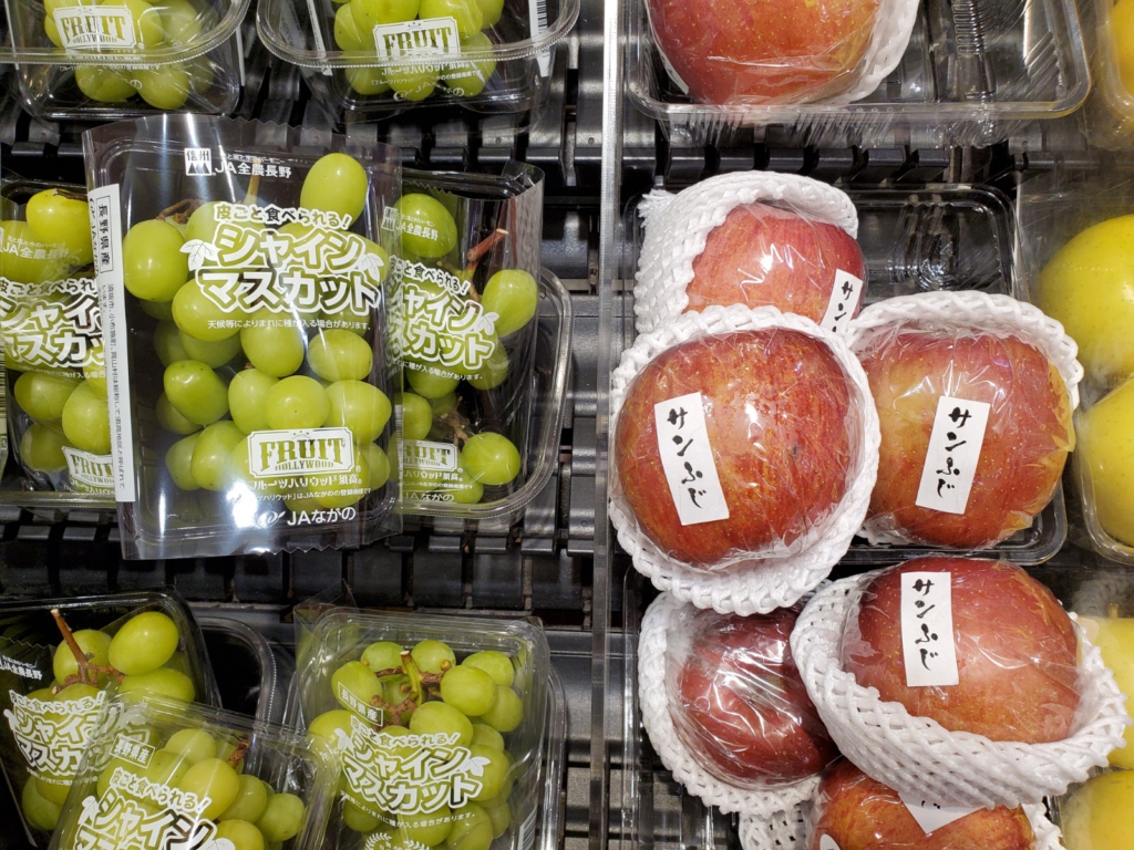 Grapes and apples wrapped in plastic in grocery store