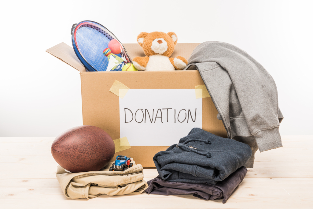 Clothes and toys in and in front of cardboard box for donation