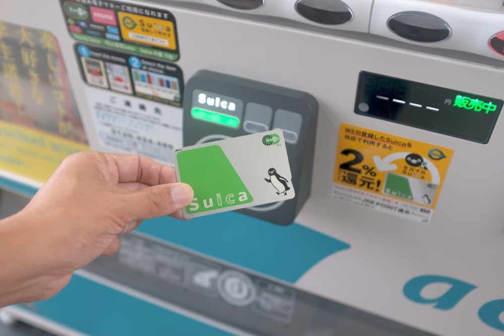 一隻手拿suica卡在自動販賣機的結帳區感應卡片